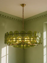 Soleil 31.5-inch olive-green glass disc chandelier hanging in a plaster-moulded corner