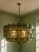 Soleil 37.4-inch olive-green glass disc chandelier hanging in a plaster-moulded corner