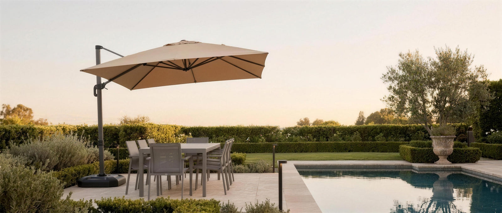 Belvara umbrella shading a poolside dining set at golden hour — lifestyle